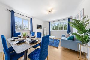 a dining room with a table and blue chairs at Spacious 2 bedroom flat by Zen Abodes Short Lets & Serviced Accommodation with Free Parking & Free Wifi in Watford