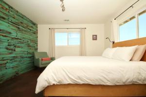 a bedroom with a white bed and a green accent wall at Mayfair House - 4 Minutes to National Park! in Twentynine Palms