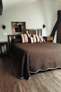 1 dormitorio con 1 cama con manta marrón en Apartamentos Rurales Casa el Abad en San Pelayo de Tehona