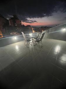una mesa y 2 sillas en un balcón por la noche en Cobertura central /com ar, en Caxias do Sul