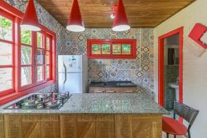 a kitchen with a stove and a refrigerator at Hotel Praia Do Rosa in Praia do Rosa