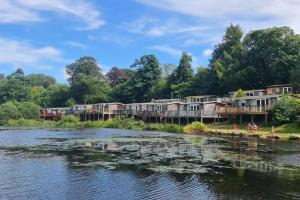 a group of houses on the side of a river at Lakeside Lodge 84 in Caeathro