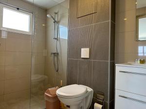 a bathroom with a toilet and a glass shower at MERAKII SEAVIEW ESCAPE CURACAO in Willemstad