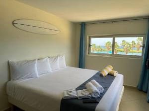 1 dormitorio con 1 cama con toallas y ventana en MERAKII SEAVIEW ESCAPE CURACAO, en Willemstad