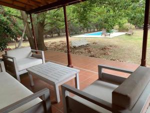 un patio con mesa, sillas y piscina en Casa con piscina y gran parque en Los Cardales en Los Cardales
