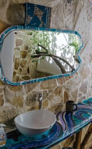 a bathroom sink with a mirror on a stone wall at Caracolito in Las Peñitas