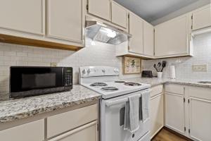 a white kitchen with a stove and a microwave at Comfortable Greensboro Condo in Greensboro