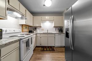a kitchen with white cabinets and a stainless steel refrigerator at Comfortable Greensboro Condo in Greensboro +14 photos