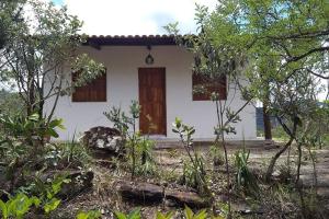 Casa blanca con puertas marrones y árboles en Chalé Mirante do Vale en Piatã