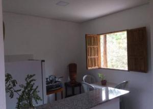 a kitchen with a refrigerator and a table and a window at Chalé Mirante do Vale in Piatã
