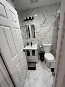 a white bathroom with a toilet and a sink at jfk 5 min away in Cedar Manor