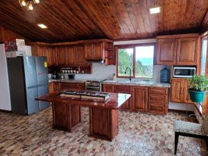 a large kitchen with wooden cabinets and a refrigerator at Casita Luna de Miel in Nabón