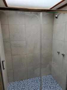 een douche met een glazen deur in de badkamer bij Casa 89 in Nabón