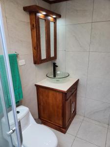 een badkamer met een wastafel, een toilet en een spiegel bij Casa 89 in Nabón