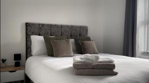 Un dormitorio con una cama blanca con toallas. en Holyhead central stay en Holyhead