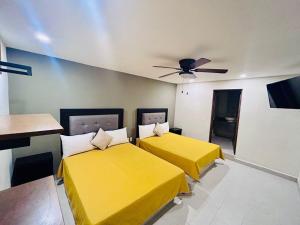 Cette chambre dispose de 2 lits jaunes et d'un ventilateur de plafond. dans l'établissement Hotel Casa 20, à León