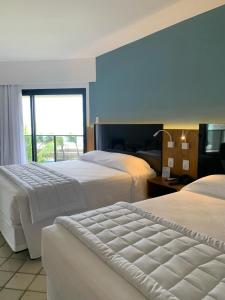 Cette chambre comprend 2 lits et une fenêtre. dans l'établissement Pirâmide palace resort, à Natal