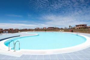 a large swimming pool with a blue sky in the background at HolaOla HighClass Townhouse in Lajares