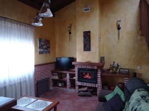 a living room with a fireplace and a tv at casa rural EL RINCON in Navadijos