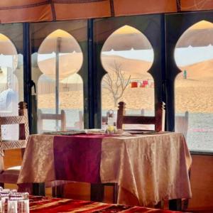 a table in a room with a view of the desert at East Coast Opulent Camp in Merzouga