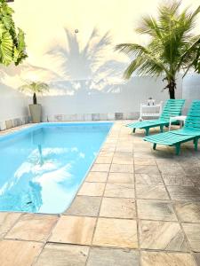 una piscina con due sedie blu e palme di Casa com piscina em Piratininga a Niterói