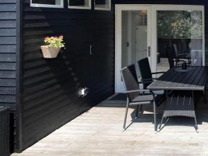 een patio met een tafel en stoelen en een plant bij 4 person holiday home in R m in Lakolk