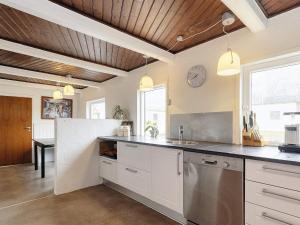 a kitchen with white cabinets and a clock on the wall at 12 person holiday home in Aabybro in Åbybro