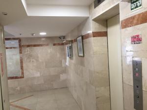 a walk in shower in a room with a stone wall at Apartment By The Lake in Tiberias