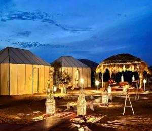 a man standing in front of a tent at night at Desert Coast Opulent Camp in Merzouga