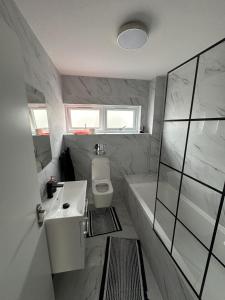 a bathroom with a sink and a toilet and a bath tub at Brand new suit room 10 min to walk central line! in Woodford