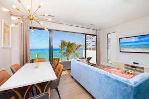 Silver Reef 2 Oceanfront Condo في North Side: غرفة معيشة مع أريكة زرقاء وطاولة مع كراسي
