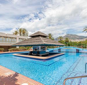 uma grande piscina com um grande guarda-sol ao lado de um edifício em Apartamentos HOLIDAYS BENALBEACH em Benalmádena