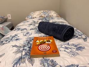 un libro sentado en una cama al lado de un objetivo en Charmoso e Acolhedor Espaço no Coração de BC, en Balneário Camboriú
