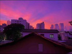 una puesta de sol sobre una ciudad con un edificio en primer plano en Charmoso e Acolhedor Espaço no Coração de BC, en Balneário Camboriú