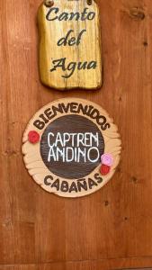 a sign on a wooden wall with a sign for a restaurant at Cabañas Captren Andino in Curacautín