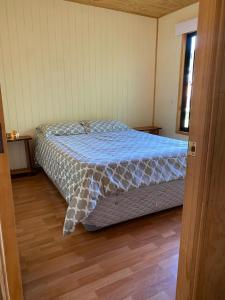 a bedroom with a bed with a blue comforter at Cabañas Captren Andino in Curacautín