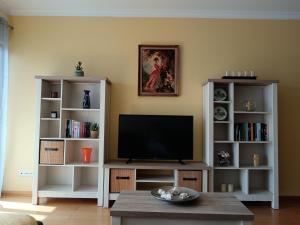 a living room with a television and white book shelves at Casa da Vila in Santa Cruz