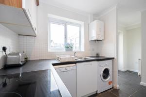 a kitchen with a sink and a washing machine at Airstays Apartment in Wythenshawe