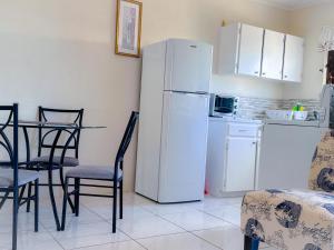 a kitchen with a white refrigerator and a table and chairs at Apartment 6, Kenridge Residences, West coast in Saint James