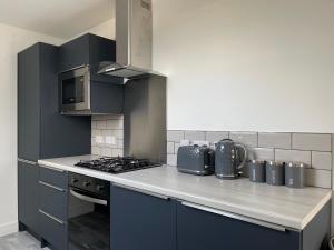 a kitchen with blue cabinets and a stove top oven at Lochside Loft - Self Catering Apartment for 2 In a great location for Inverness Airport and both Cabot Highlands & Nairn Golf Courses in Inverness