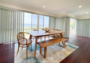 - une salle à manger avec une table, des chaises et des fenêtres dans l'établissement The Swan Lakehouse, on Budgewoi Lake, à Budgewoi