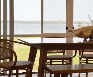 - une table et des chaises avec vue sur l'eau dans l'établissement The Swan Lakehouse, on Budgewoi Lake, à Budgewoi
