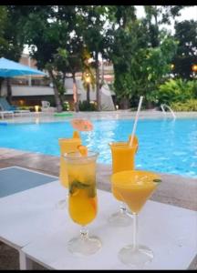 three drinks on a table next to a swimming pool at Tambuli maribago seaside living and resort in Lapu Lapu City