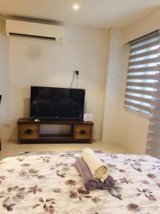 a bedroom with a bed and a flat screen tv at Tambuli maribago seaside living and resort in Lapu Lapu City