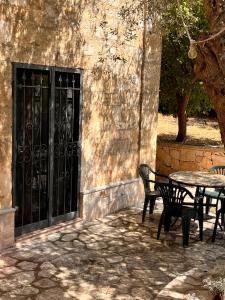 einen Tisch und Stühle neben einem Gebäude mit einem schwarzen Tor in der Unterkunft Chiave d'Arco in Selva di Fasano