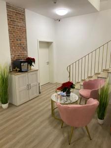 a room with a staircase and pink chairs and a table at Appartementhaus EMDEN in Emden