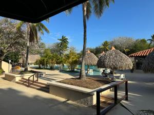 um resort com mesas e guarda-sóis de palha e uma piscina em GOLF CORONADO LUXURY MANGO SUITE PRIVATE POOL FEE INCLUDED em Playa Coronado