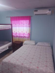 um quarto com uma cama com uma cortina rosa em HOTEL EL CASTILLO MANTA2 em Manta