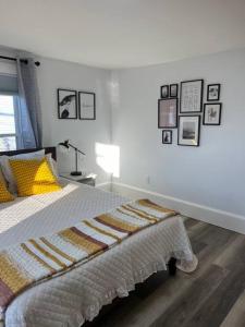 een slaapkamer met een bed met een deken en foto's aan de muur bij Remodeled Townhouse in Watertown in Watertown