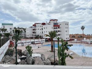 a large white building with palm trees and a pool at San Eugenio in Adeje